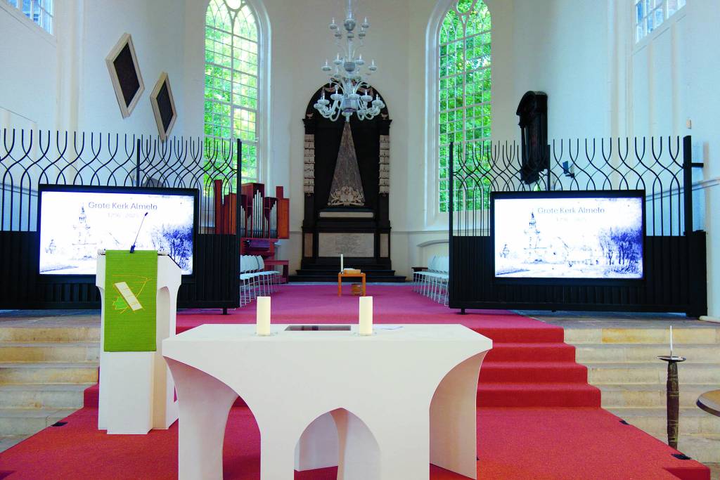 Het nieuwe liturgische centrum met daarachter het historische koordeel. De koorhekken zijn voorzien van grote beeldschermen.